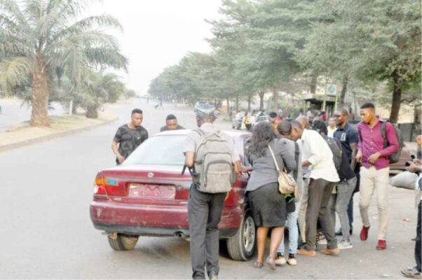 Commuters struggle to board a taxi at a bus stop in Jabi Abuja recently.