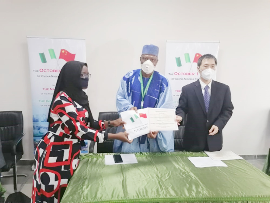 The Vice Chancellor of UniAbuja, Prof Abdul-Rasheed Na’Allah and the Charge D’Affaires of embassy of China Mr. Zhao Yong presenting grant to one of the beneficiaries in Abuja on Tuesday.