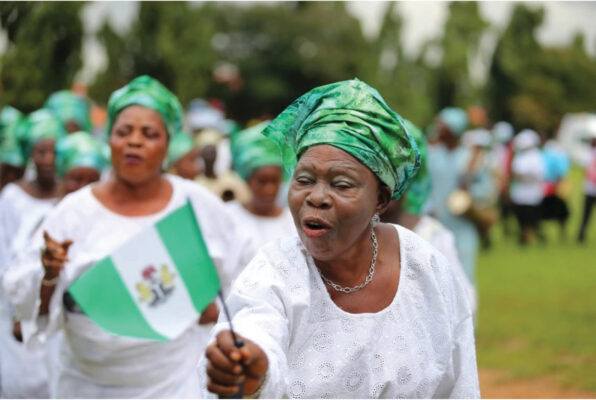 A woman raises the Nigerian flag as she participates in a parade to commemorate Nigeria’s 55th Independence Day in this 2015 photo [File: Akintunde Akinleye/Reuters]