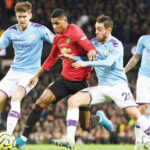 Manchester United’s Marcus Rashford being tackled by Manchester City’s John Stones and Bernardo Silva in a recent derby.