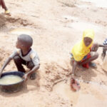 Children scooping water from the valley