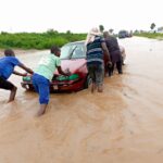 Passengers push a car that stucked inside a heavy flood at Anini village, along Abuja-Lokoja road Photo: Abubakar Sadiq Isah