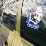 Photo shows sticker depicting Russian President Vladimir Putin as Adolf Hitler on a repaired pickup truck outside an auto repairing shop in Ukrainian capital of Kyiv on December 30, 2022. - An auto garage in Kyiv is giving beat-up cars a second life as battle-ready vehicles for Ukraine's military, trying to plug a supply gap as the war with Russia grinds on.(Photo by Sergei SUPINSKY / AFP)