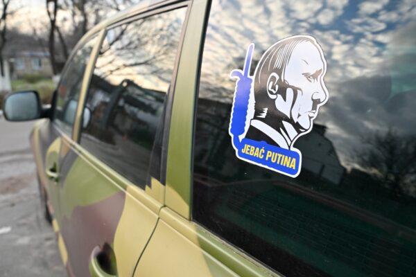 Photo shows sticker depicting Russian President Vladimir Putin as Adolf Hitler on a repaired pickup truck outside an auto repairing shop in Ukrainian capital of Kyiv on December 30, 2022. - An auto garage in Kyiv is giving beat-up cars a second life as battle-ready vehicles for Ukraine's military, trying to plug a supply gap as the war with Russia grinds on.(Photo by Sergei SUPINSKY / AFP)