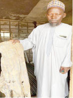 ahmad mando holding a lone trouser he found at the burial scene with spots of blood