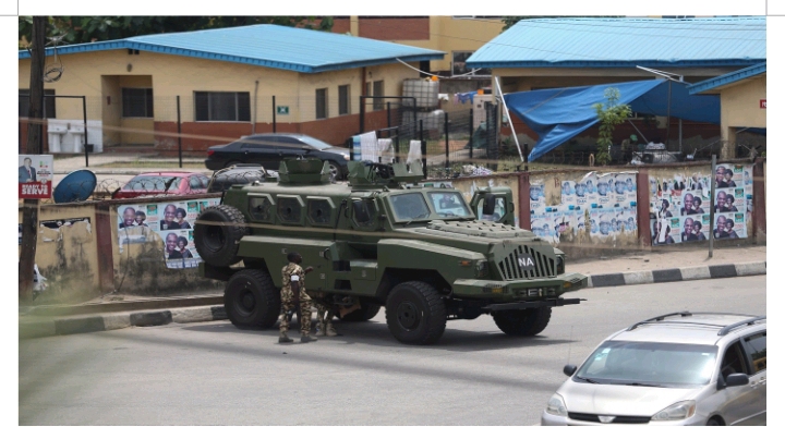 An army armored vehicle is parked next to a wall with election posters near the Independent Electoral Commission's  (INEC) office after elections in Lagos. Photograph by Akintunde Akinleye/CCIJ